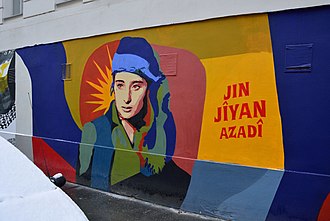 <span>Krótkie hasło – „kobieta, życie, wolność” – powtarzane przez irańskich demonstrantów przez ostatnie dwa miesiące, znalazło, jak się wydaje, globalny oddźwięk, jakiego niewielu się spodziewało. Na zdjęciu: Mural w Wiedniu ze słowami „kobieta, życie, wolność” po kurdyjsku. (Źródło: Wikipedia</span>)