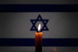 Ponca wieca na tle flagi izraelskiej w Jom Haszoah, Dniu Pamici o Holokaucie. Zdjcie: Melnikov Dmitriy/Shutterstock.