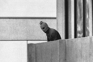 Czonek grupy Arab Commando, która zaja kwatery izraelskiej druyny olimpijskiej w wiosce olimpijskiej w Monachium, Niemcy, z kapturem na gowie stoi na balkonie budynku, w którym komandosi przetrzymywali zakadników, 5 wrzenia 1972 roku. ródo: AP Photo/Russell McPhedran via Wikimedia Commons.