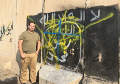Autor obok graffiti Pastwa Islamskiego w Szingal w Iraku, miecie, które zostao wyzwolone od ekstremistów w listopadzie 2015 r.(zdjcie: SETH J. FRANTZMAN).