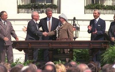 Bill Clinton patrzy jak Icchak Rabin i Jaser Arafat podają sobie ręce podczas historycznego podpisywania Umów z Oslo, 13 września 1993 roku. (GPO)