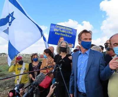 Sven Kühn von Burgsdorff (in the blue shirt) and mysterious European diplomats. Behind them a group of protesters with a banner stating: “European Union: your money killed Rina Shnerb R.I.P.”