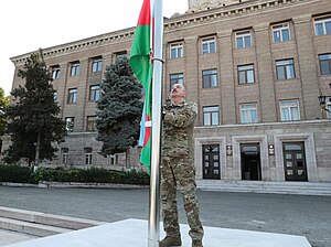 Podczas bombardowań Azerbejdżanu 19 września 2023 r. w Arcach zamordowano setki cywilów, w tym dzieci. Od tego czasu prawie wszyscy Ormianie z Arcach uciekli: wiedzą, że po wszystkich nalotach wojskowych Ormianie, którzy wpadli w ręce azerbejdżańskiej armii, byli traktowani z maksymalnym okrucieństwem. Na zdjęciu: Prezydent Azerbejdżanu 15 października 2023r  wciąga flagę swojego kraju przed rezydencja prezydenta Górskiego Karabachu w Stepanakercie. (Źródło: Wikipedia) 