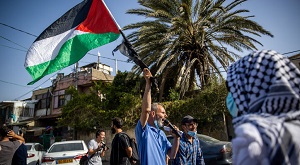Mężczyzna wymachuje palestyńską flagą podczas demonstracji w dzielnicy Jerozolimy, Szejk Dżarrah, 16 kwietnia 2021 r. (Flash90/Yonatan Sindel)