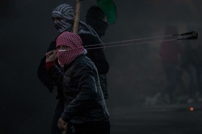 Palestyczyk z proc ciska kamienie na izraelskiego stranika granicznego w pobliu Ramallah, 9 grudnia 2017. (Zdjcie: Chris McGrath/Getty Images)