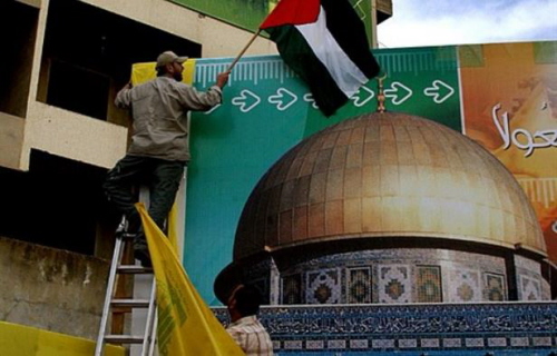 Czonek Hezbollahu zawiesza flag palestysk nad olbrzymim plakatem meczetu Al-Aksa w dniu 19 padziernika 2006 r. w libaskim miecie Nabatieh. (AFP/Mustapha Mahmoud)