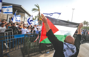 MĘŻCZYZNA demonstruje z palestyńską flagą naprzeciwko grup wznoszących izraelskie flagi na Starym Mieście w Jerozolimie podczas obchodów Dnia Jerozolimy w zeszłym tygodniu.(źródło zdjęcia: JAMAL AWAD/FLASH90)
