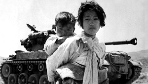 Koreańska dziewczyna z bratem na plecach przechodzi obok amerykańskiego czołgu w Haengju. Zdjęcie majora RV Spencera, UAF (marynarka wojenna). US Army Korea, 9 czerwca 1951 r. Wikicommons.