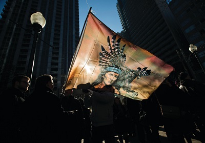 Sylwetki protestujcych z Pierwszego Narodu widoczne za flag podczas demonstracji w Toronto w 2013 r. (zdjcie: REUTERS)