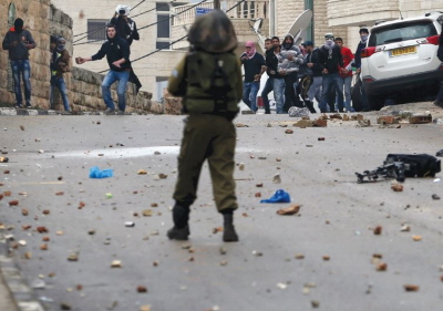 MODZIE PALESTYSKA ciska kamieniami w onierzy armii izraelskiej podczas star w miecie Ramallah na Zachodnim Brzegu w pitek. (zdjcie: REUTERS)