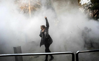 Na zdjciu: moda kobieta protestuje, podczas gdy w tle iraskie siy bezpieczestwa rozpdzaj tum gazem zawicym. 