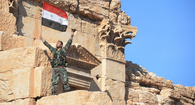 Syryjska flaga narodowa powiewa na tle ruin historycznego miasta Palmira w prowincji Homs w Syrii. 1 kwietnia 2016 r.
