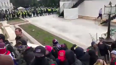 (Zdjcie –  policja przyglda si jak tum szturmuje Kapitol. Zrzut z ekranu z wideo, które jako znika z Facebooka bez informacji dlaczego  https://www.israelunwired.com/never-before-seen-footage-police-let-crowd-walk-into-the-capitol-building/ )